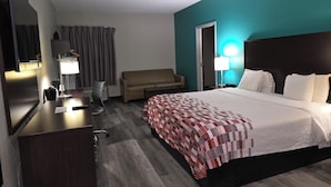 A hotel room with a bed, a desk, a chair, a sofa, and a TV. - Sonesta Essential Ames (Ames)
