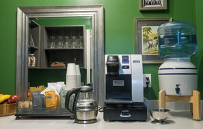 Una estación de café con una máquina Keurig, un dispensador de agua y un molinillo de café.