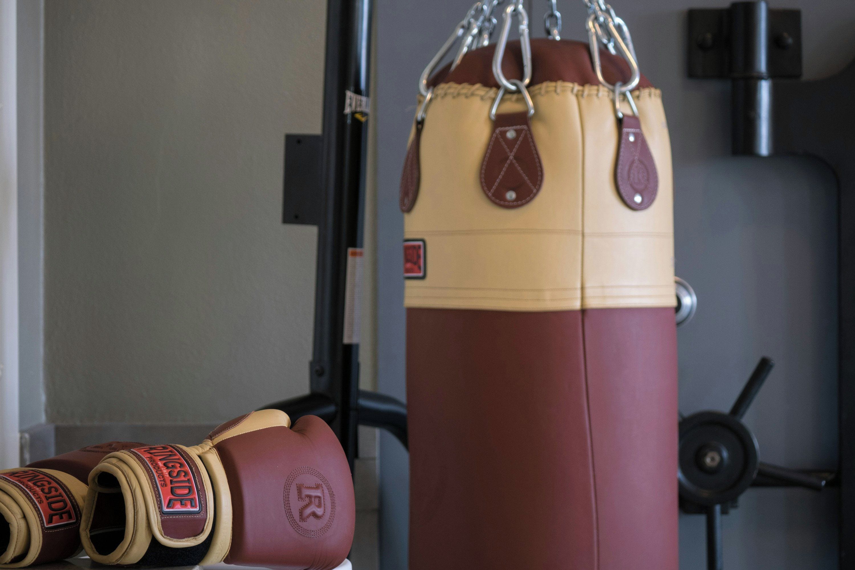 A punching bag with a weight scale and boxing gloves on the floor.