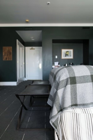 A hotel room with a bed, a desk, and a chair. There is a door leading to another room. - Sentinel Hotel (Portland)
