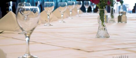 Une table dressée avec des verres à vin, un vase contenant une fleur, ainsi que des salières et des poivrières.