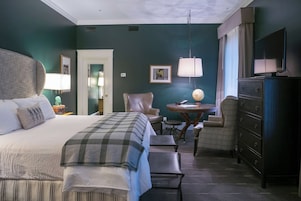 Une chambre d’hôtel avec un grand lit, un bureau, une chaise, une commode et un téléviseur.