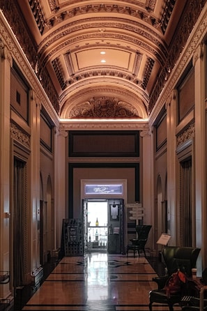 A grand lobby with ornate ceiling and columns, a wine lounge sign, and a seating area with chairs. - Sentinel Hotel (Portland)