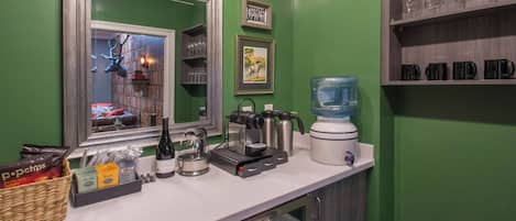 A kitchenette with a coffee maker, kettle, blender, and a water dispenser.