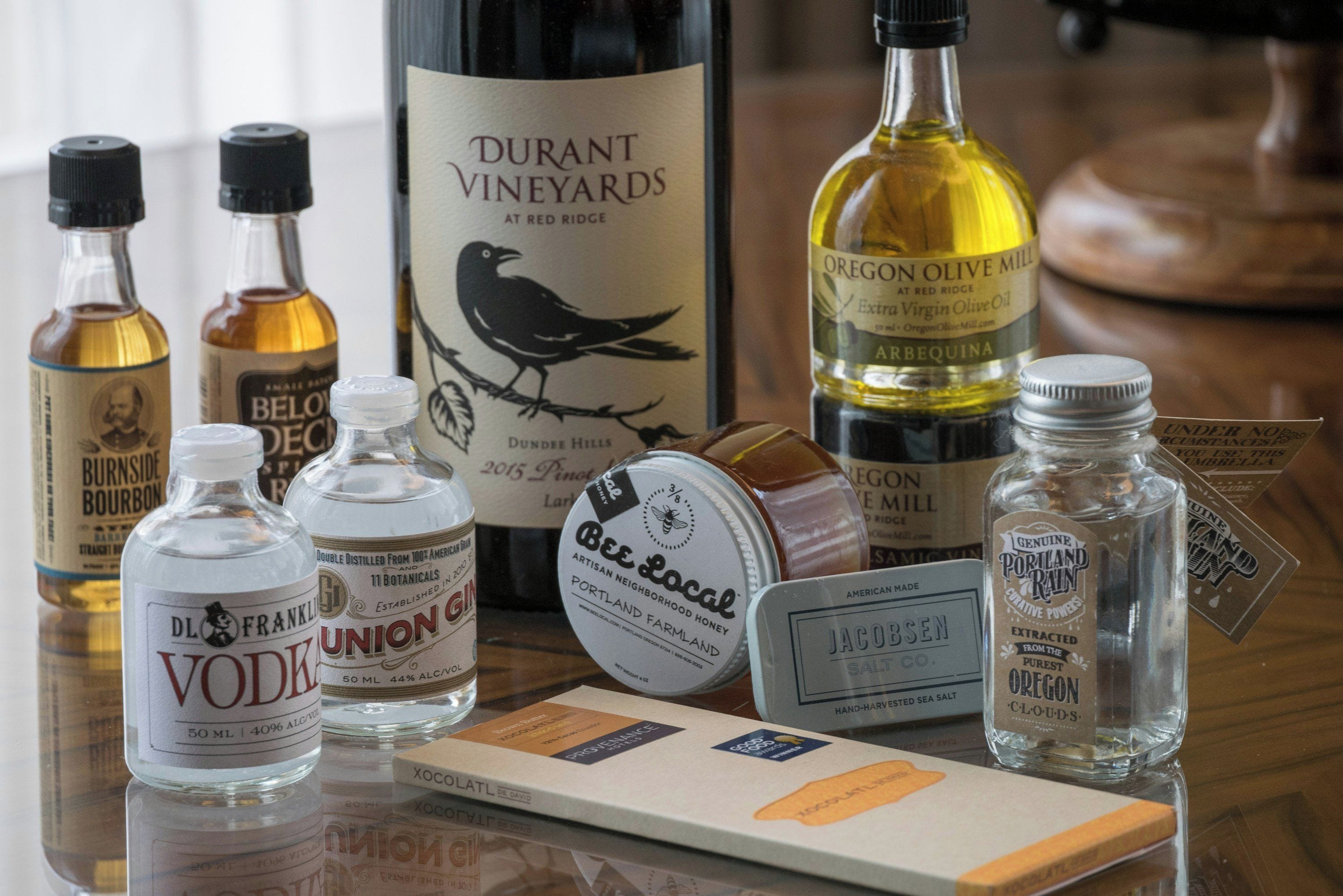 A selection of bottled beverages and condiments on a reflective surface.