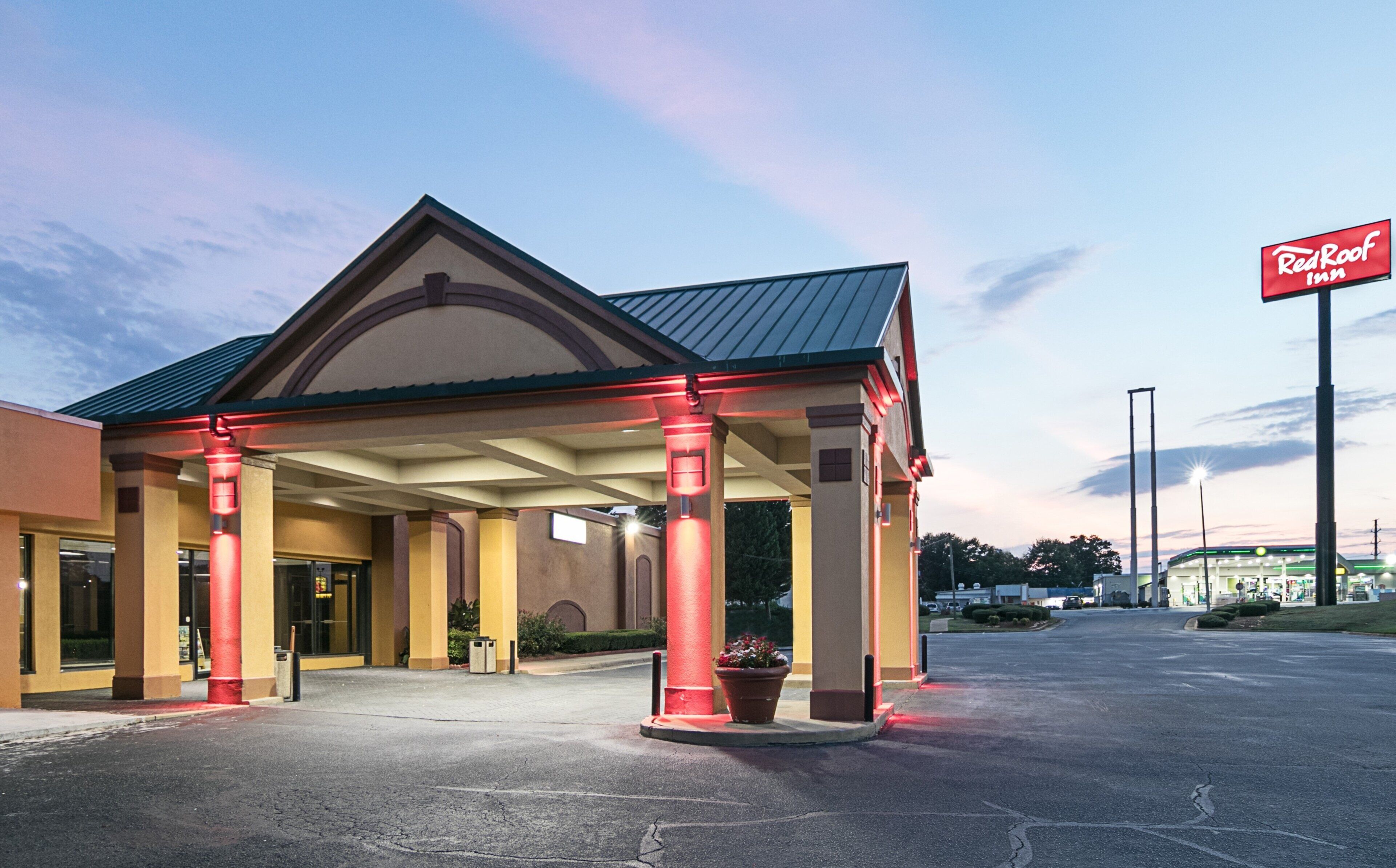 Un Red Roof Inn con entrada techada, estacionamiento y cielo despejado.