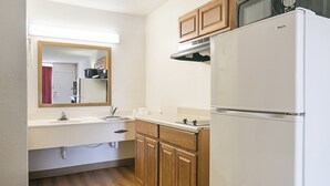 A compact kitchen with a refrigerator, microwave, and wooden cabinets. - Red Roof Inn Forsyth (Forsyth)