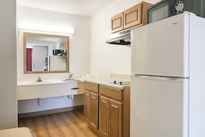 A compact kitchen with a refrigerator, microwave, and wooden cabinets. - Red Roof Inn Forsyth (Forsyth)