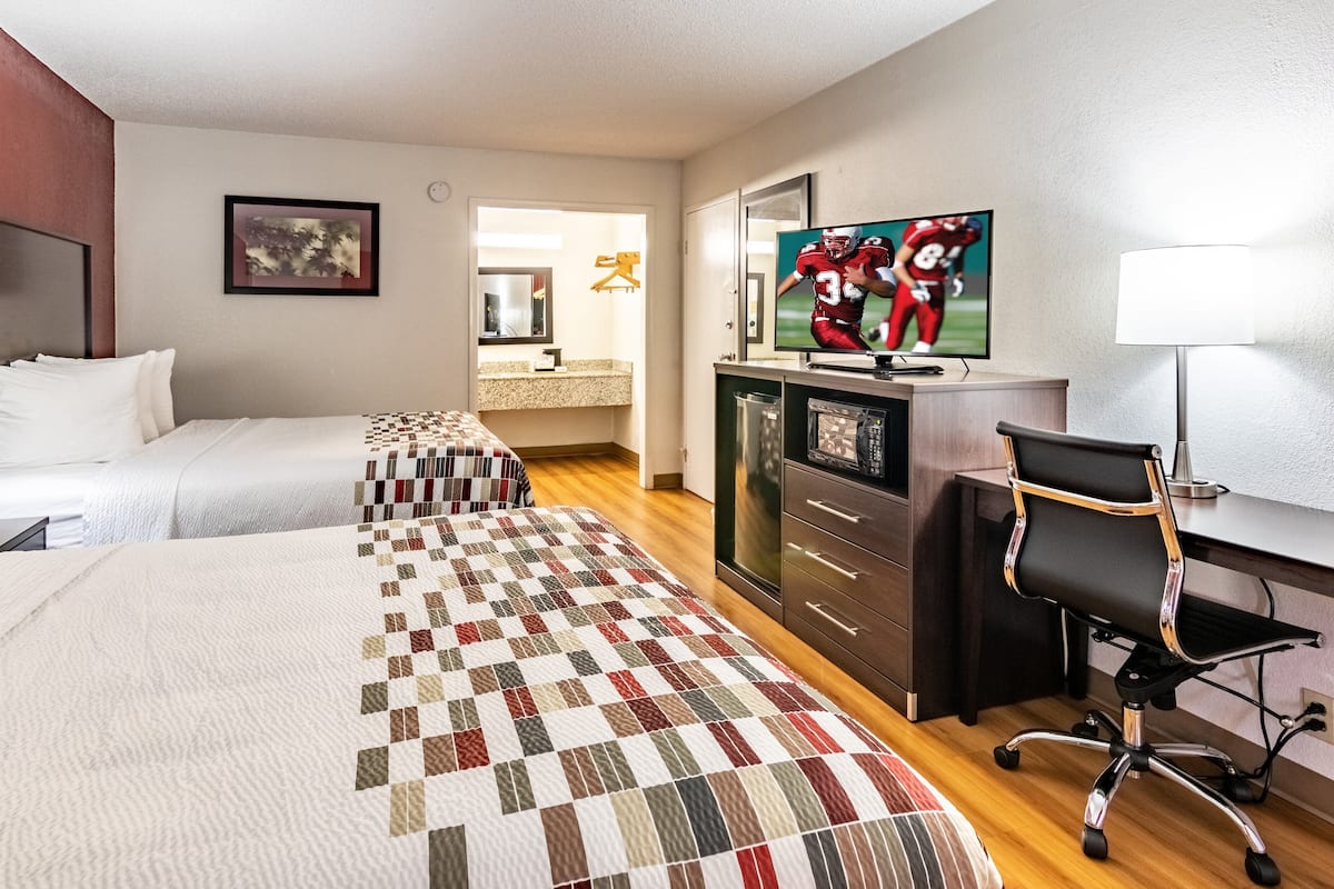 Una habitación de hotel con dos camas, un escritorio, un televisor y una silla.