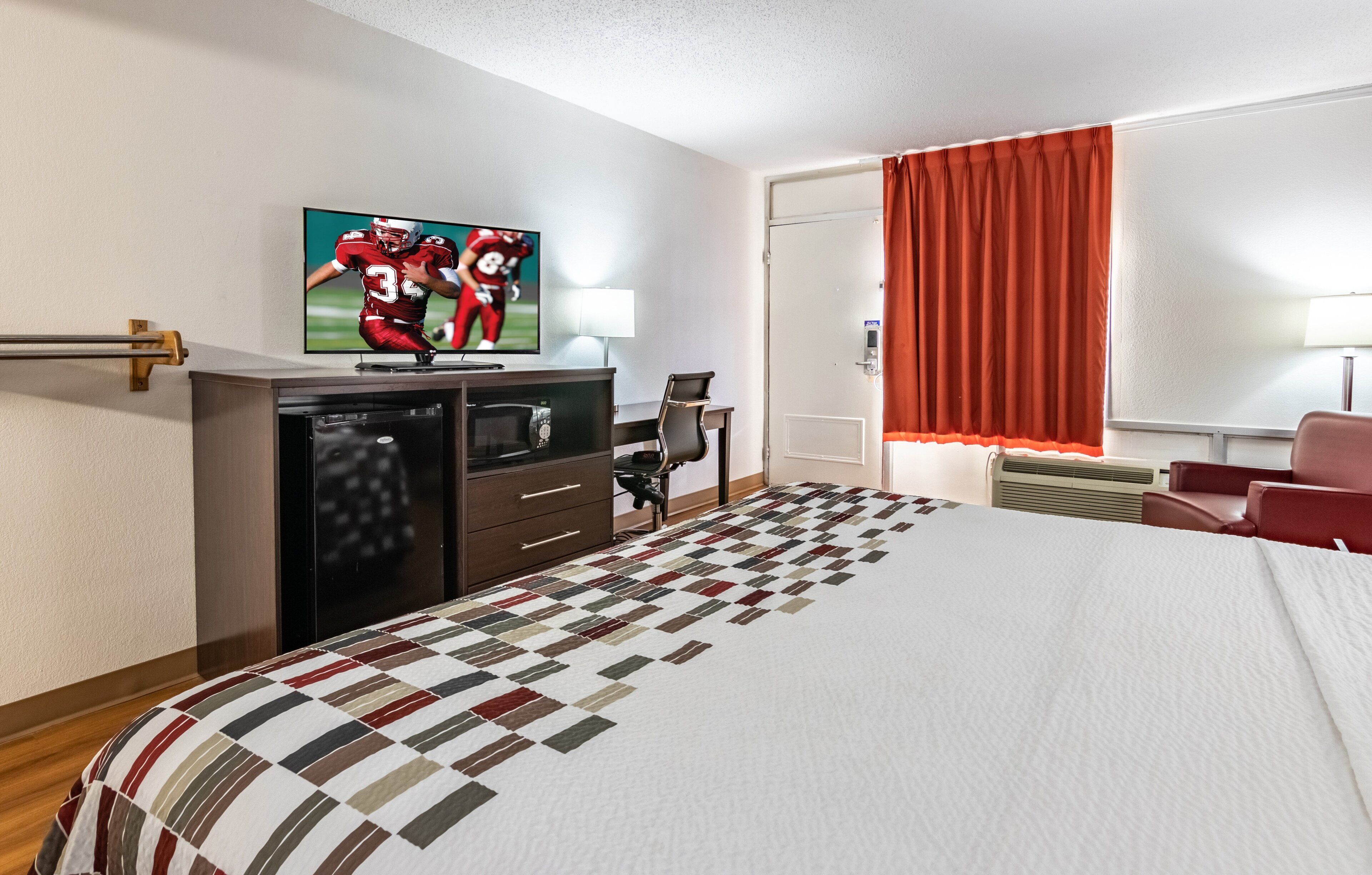 A hotel room with a bed, a television, a desk, and a chair.