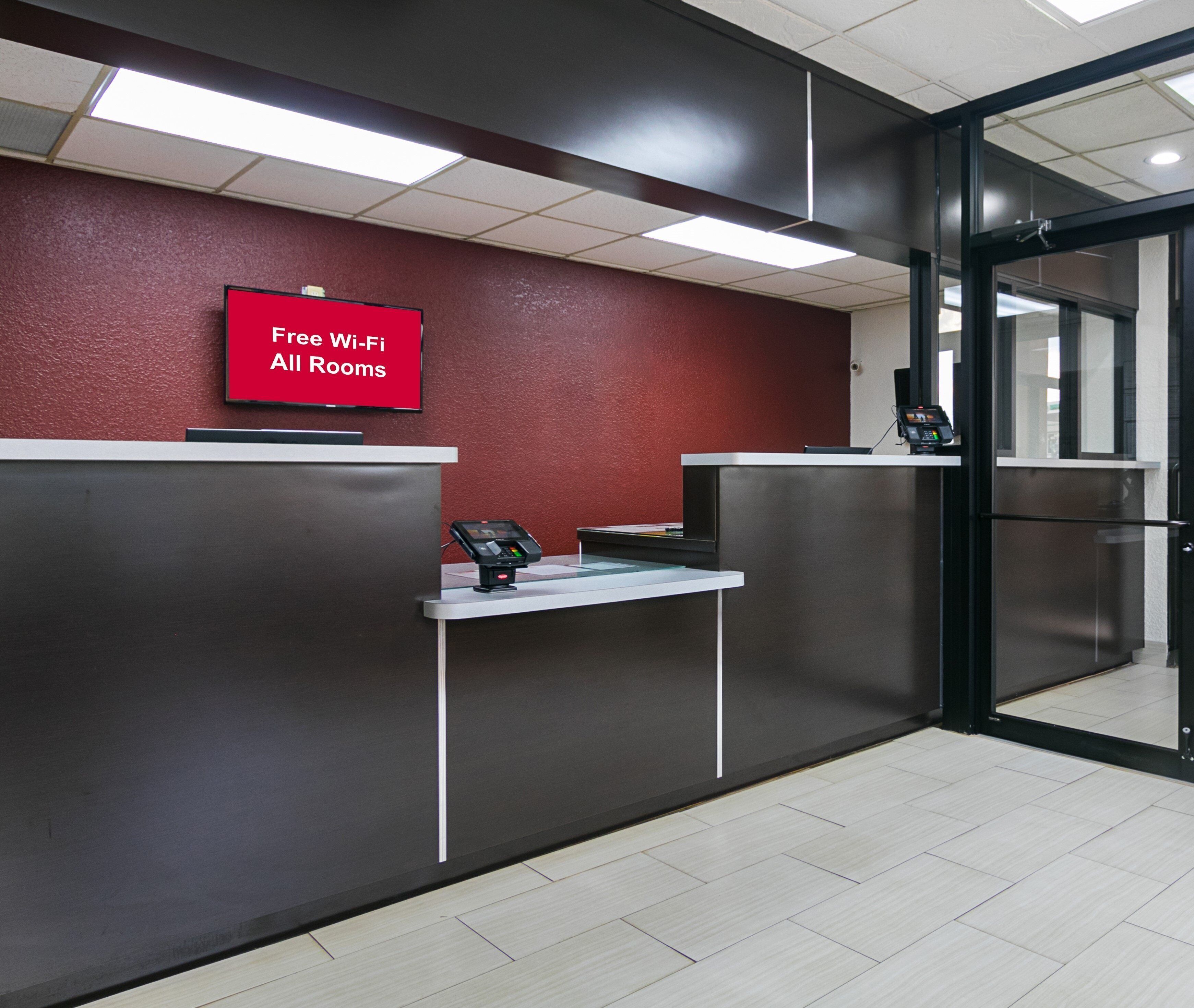 Mostrador de recepción con pantalla digital que muestra 'Wi-Fi gratis en todas las habitaciones' y un terminal de pago.