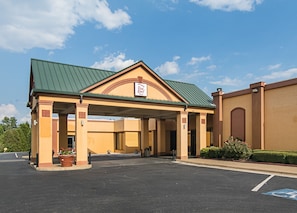 A Red Roof Inn with a covered entrance, a parking lot, and a clear sky.