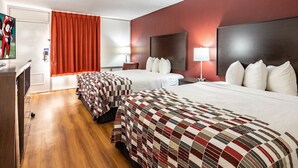 A hotel room with two beds, a desk, a TV, and a red curtain. - Red Roof Inn Forsyth (Forsyth)