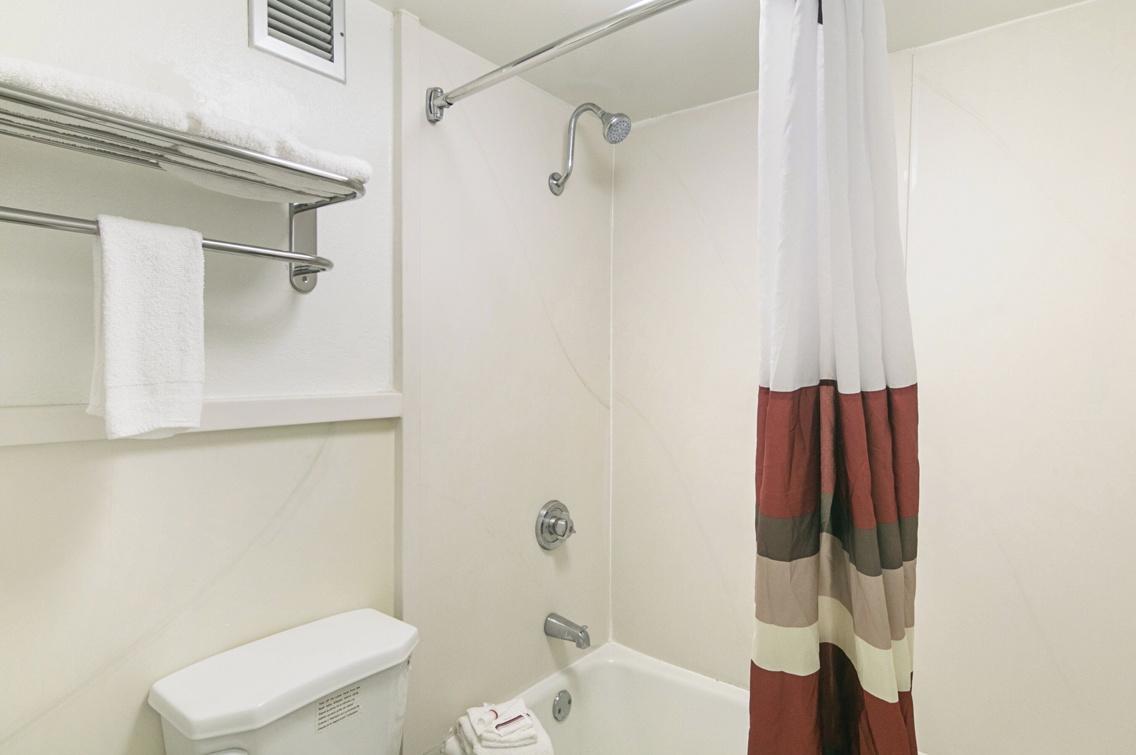 A bathroom with a shower, toilet, and towel rack.