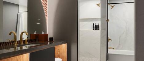 A modern bathroom with a vanity, a large mirror, a shower with a glass door, and a bathtub.