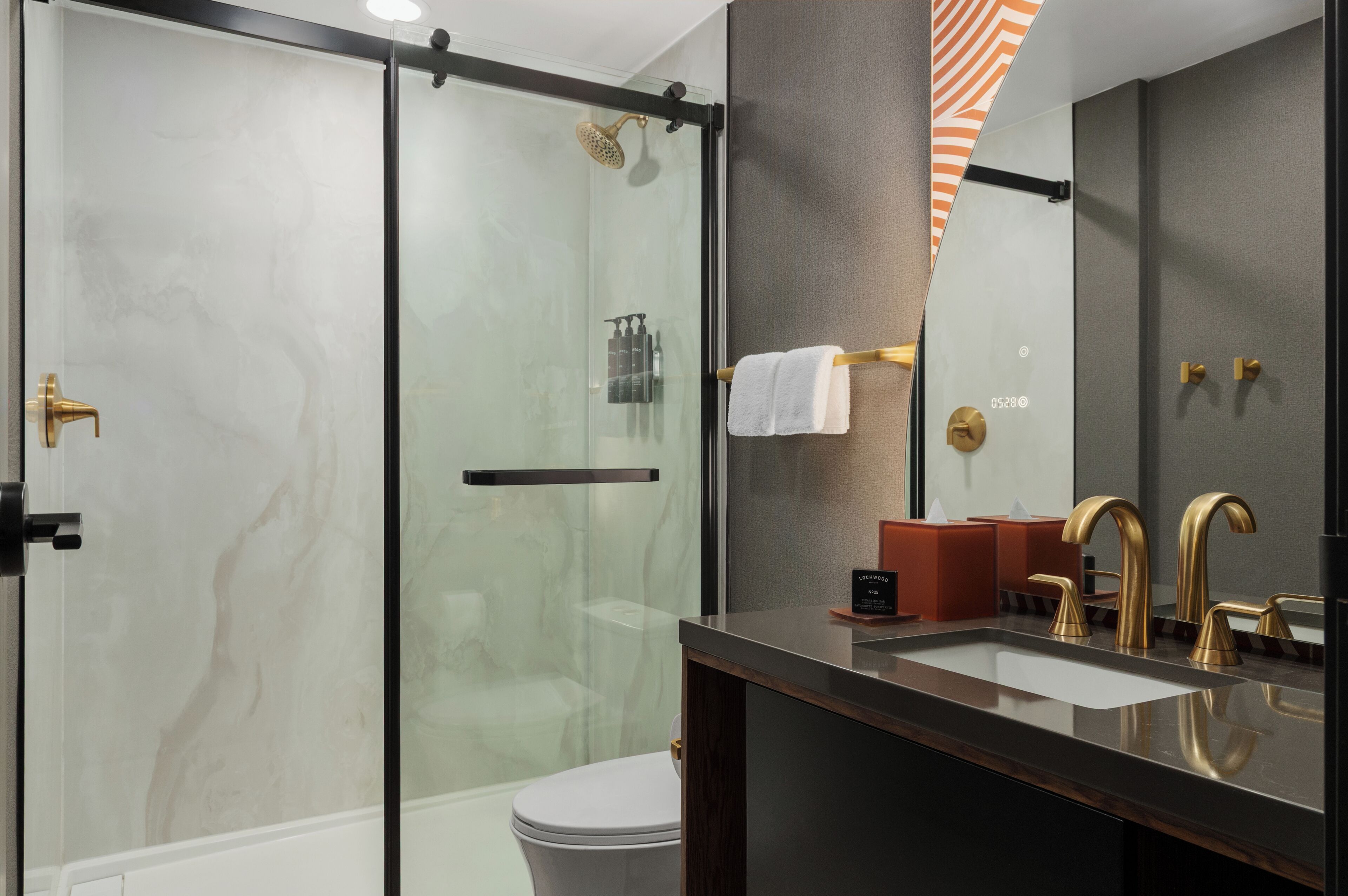 A modern bathroom with a glass-enclosed shower, a vanity with a sink, and a large mirror.