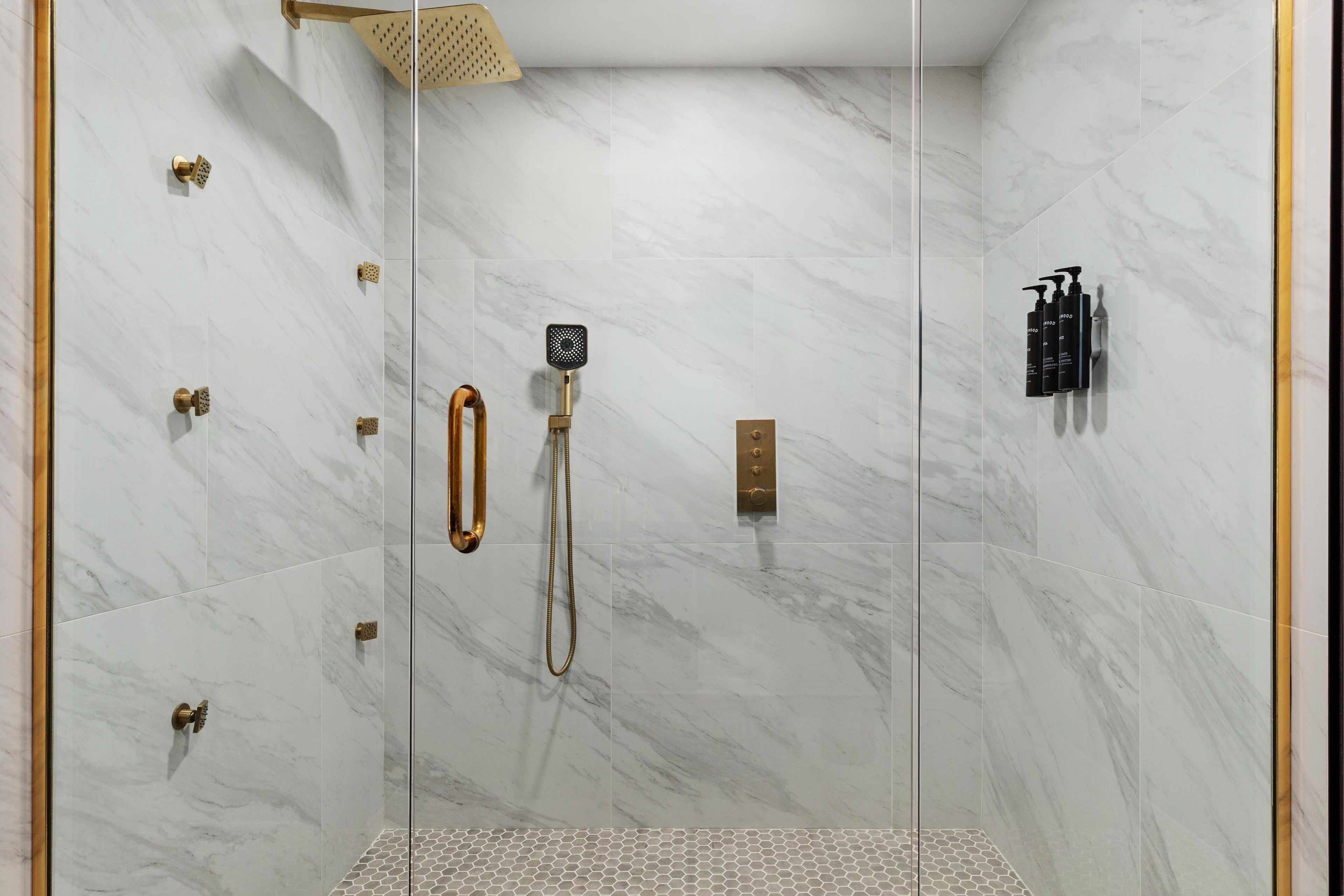 A modern shower with a handheld showerhead, a handheld shower, and a wall-mounted showerhead.