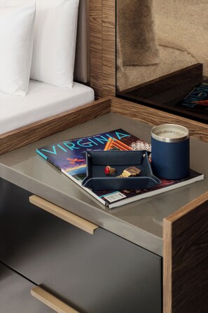 A neatly arranged hotel room with a bed, a bedside table, a magazine, a cup, and a watch. - The Berkeley Richmond, Outset Collection by Hilton (Richmond)