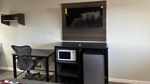 A compact room with a bed, a desk with a computer, a chair, and a microwave. - Rodeway Inn Jonesboro - Atlanta South (Forest Park)
