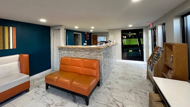 A hotel lobby with a seating area, a reception desk, and a television. - Rodeway Inn Jonesboro - Atlanta South (Forest Park)