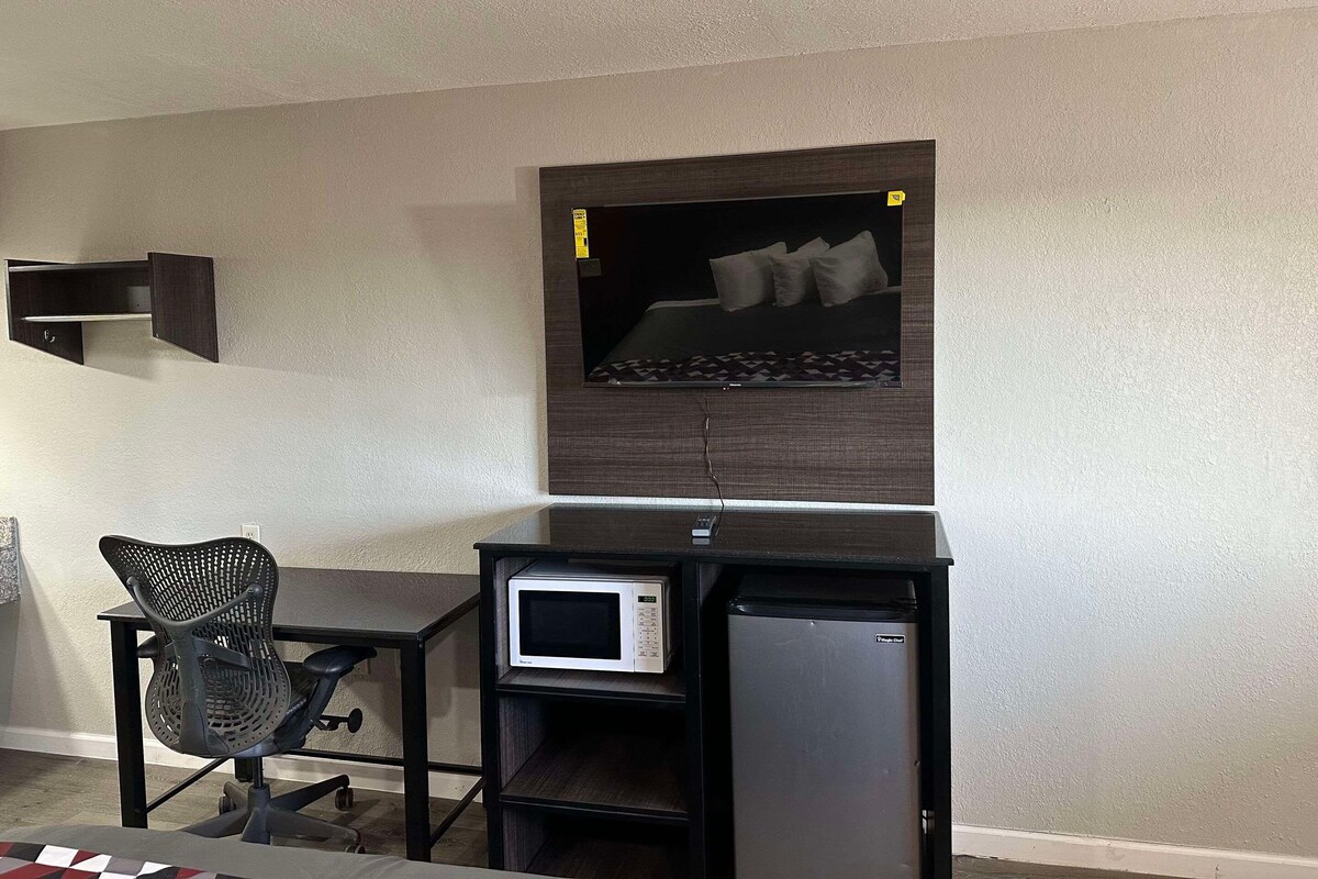 Una habitación pequeña con una cama, un escritorio con una computadora y una silla.