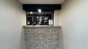A reception area with a tiled wall, a black-framed window, and a 'NOTICE PLEASE RING BELL' sign. - Rodeway Inn Jonesboro - Atlanta South (Forest Park)