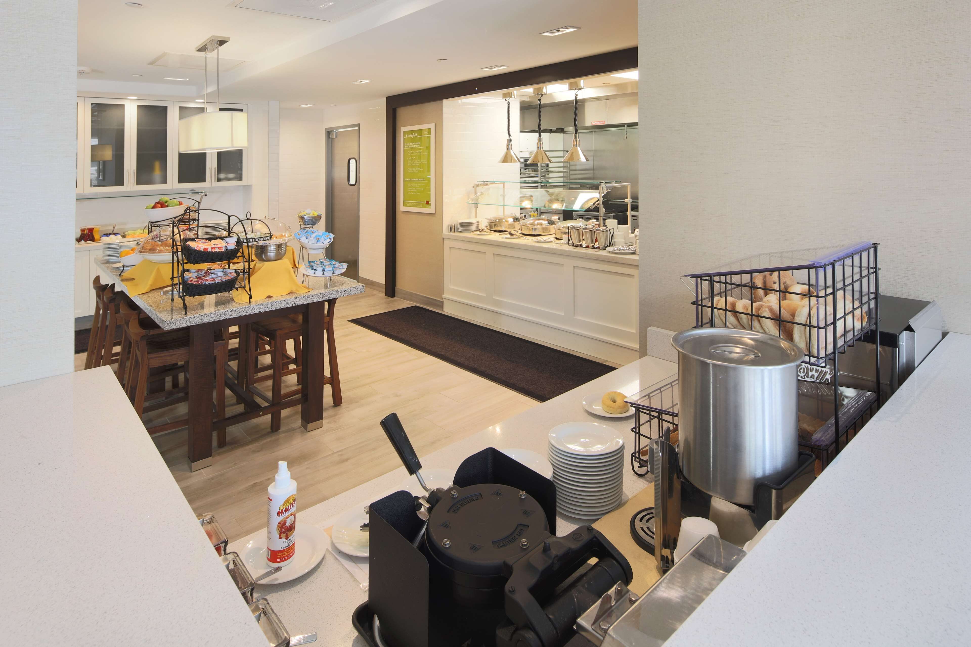 Une cuisine moderne dotée d’un îlot central, d’un coin repas avec des chaises et d’un buffet.