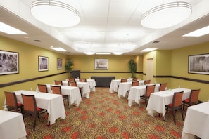 A conference room with multiple tables and chairs, a patterned carpet, and framed pictures on the walls. - Holiday Inn Portsmouth by IHG (Portsmouth)