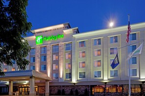 Un bâtiment d'hôtel Holiday Inn, reconnaissable à son grand panneau vert, à ses nombreuses fenêtres et au drapeau américain qui y flotte.