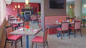 A restaurant with booths and tables, a flat-screen TV mounted on the wall, and a patterned carpet. - Holiday Inn Portsmouth by IHG (Portsmouth)
