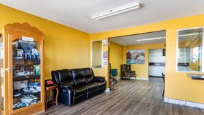 Una habitación con un sofá de cuero negro, un aparador para zapatos y un armario de madera.