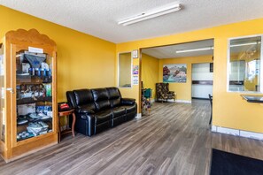 A room with a black leather sofa, a shoe display cabinet, and a wooden cabinet. - Econo Lodge Gallup West (Gallup)