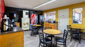 Una habitación de hotel compacta con kitchenette, un comedor con mesa y sillas, un refrigerador, un microondas y un ventanal grande.