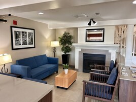 A living room with a blue sofa, a wooden coffee table, a fireplace, and a staircase leading to an upper level.
