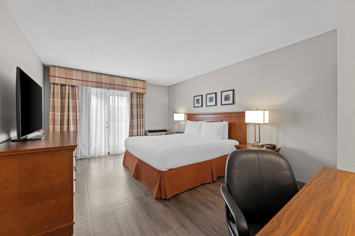 A hotel room with a bed, a desk, a television, a lamp, and a chair.