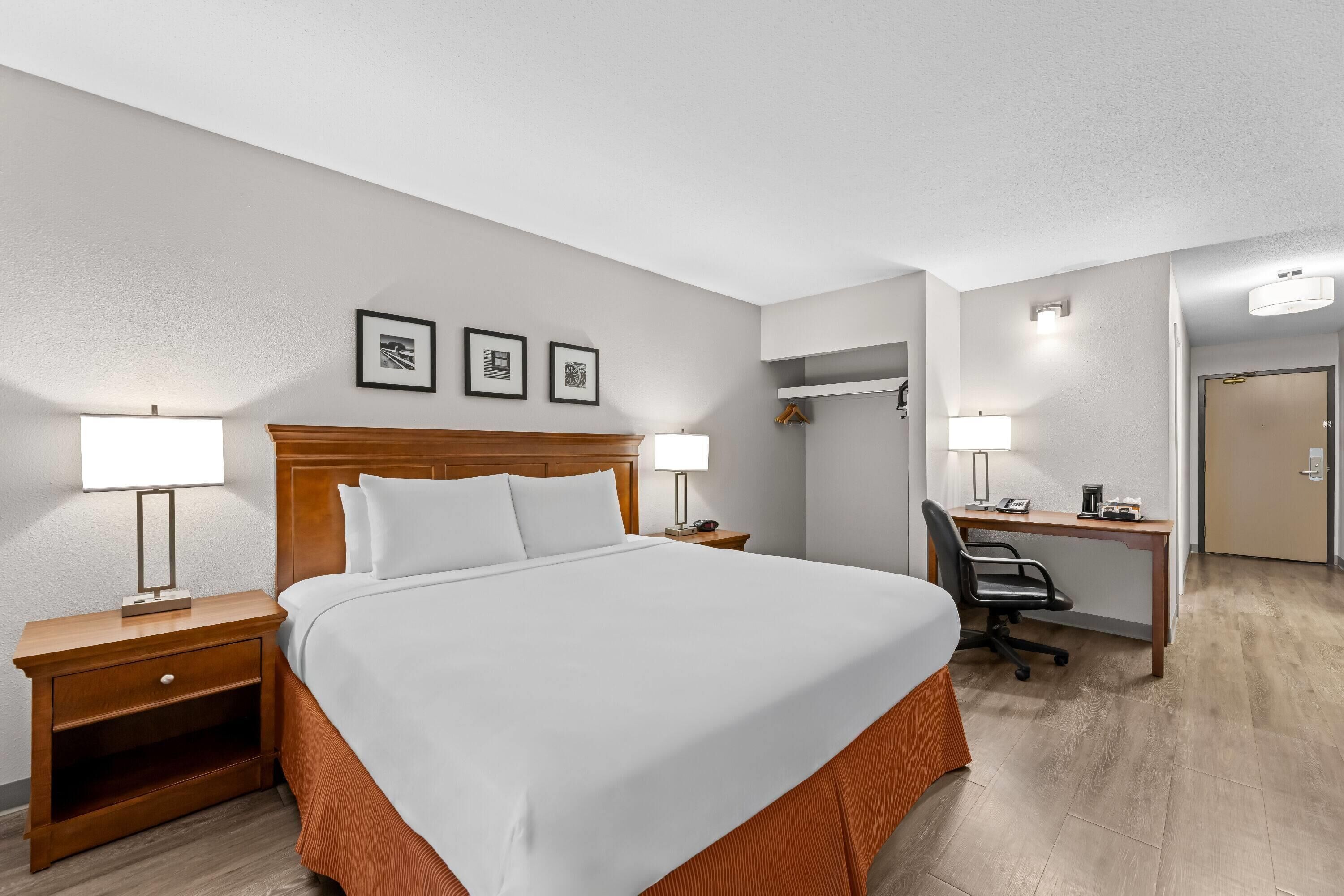 Una habitación de hotel con cama, mesitas de noche, escritorio y silla.