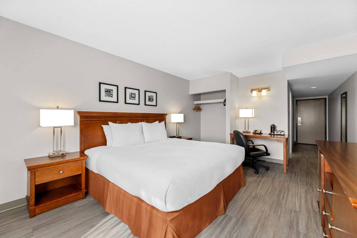 A hotel room with a bed, bedside tables, a desk, and a chair.