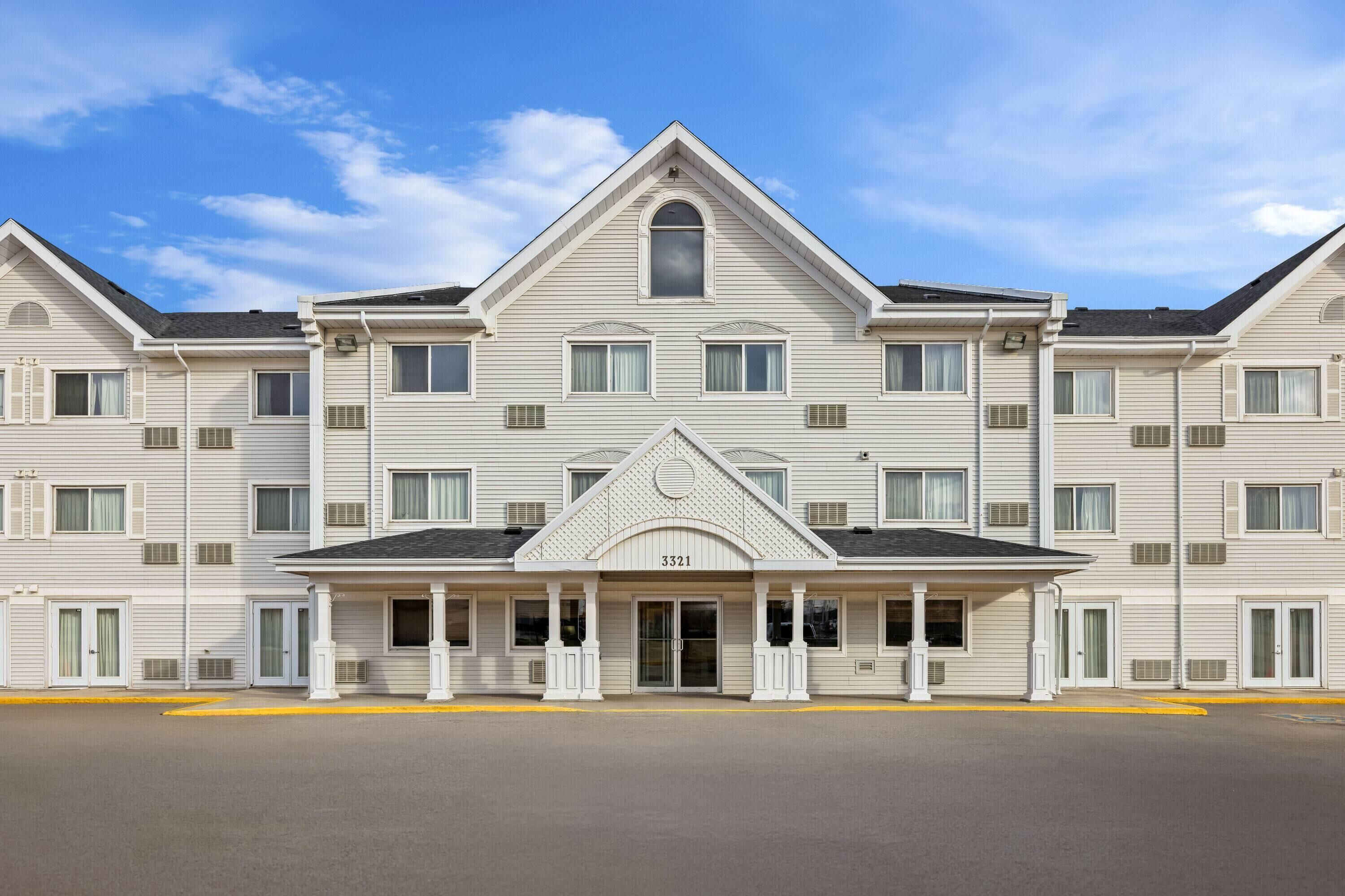 A multi-story hotel with a symmetrical facade, a central entrance with a door and windows, and a number '3321' displayed above the entrance.