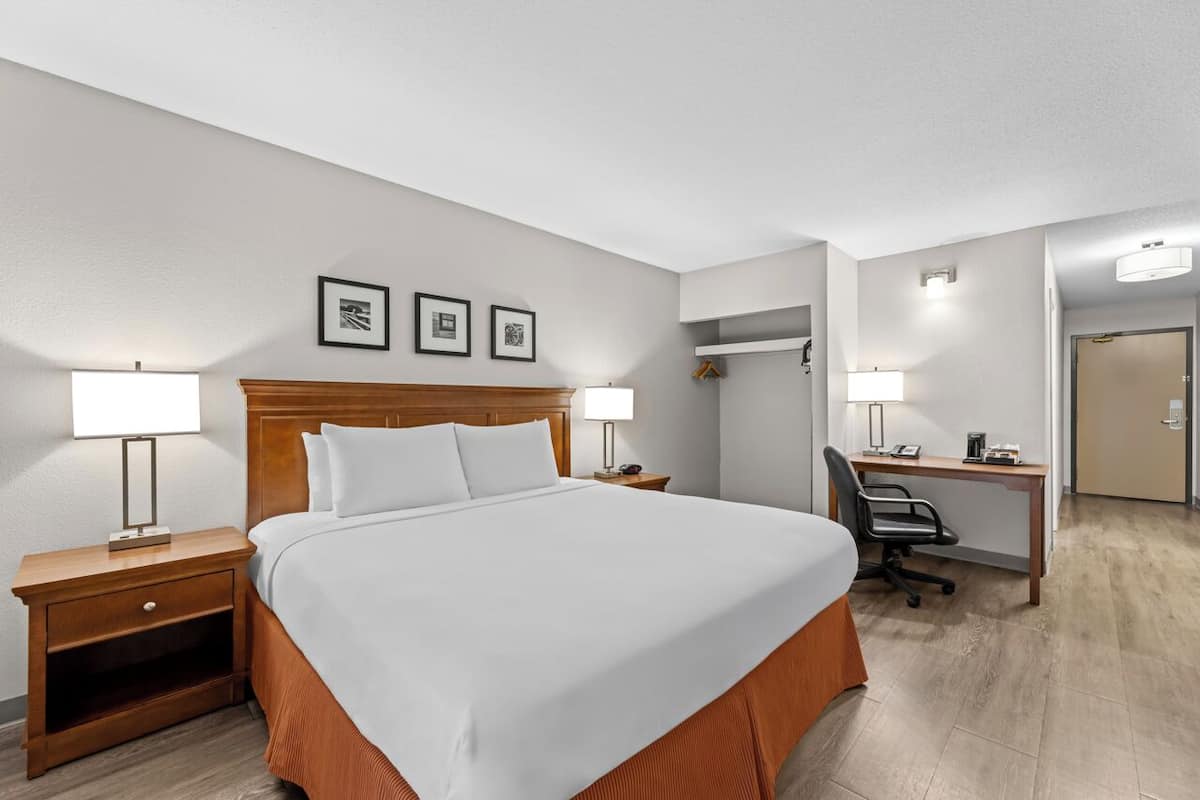 A hotel room with a bed, two bedside tables, a desk, and a chair.