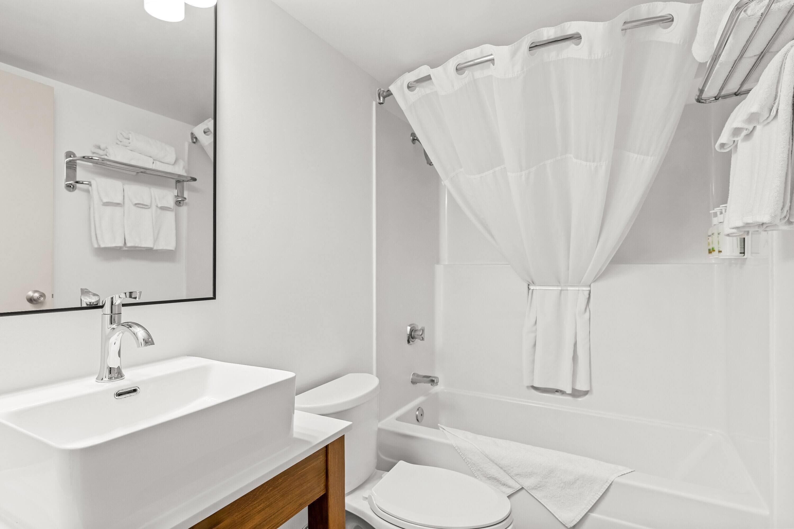 A modern bathroom with a sink, toilet, and bathtub.