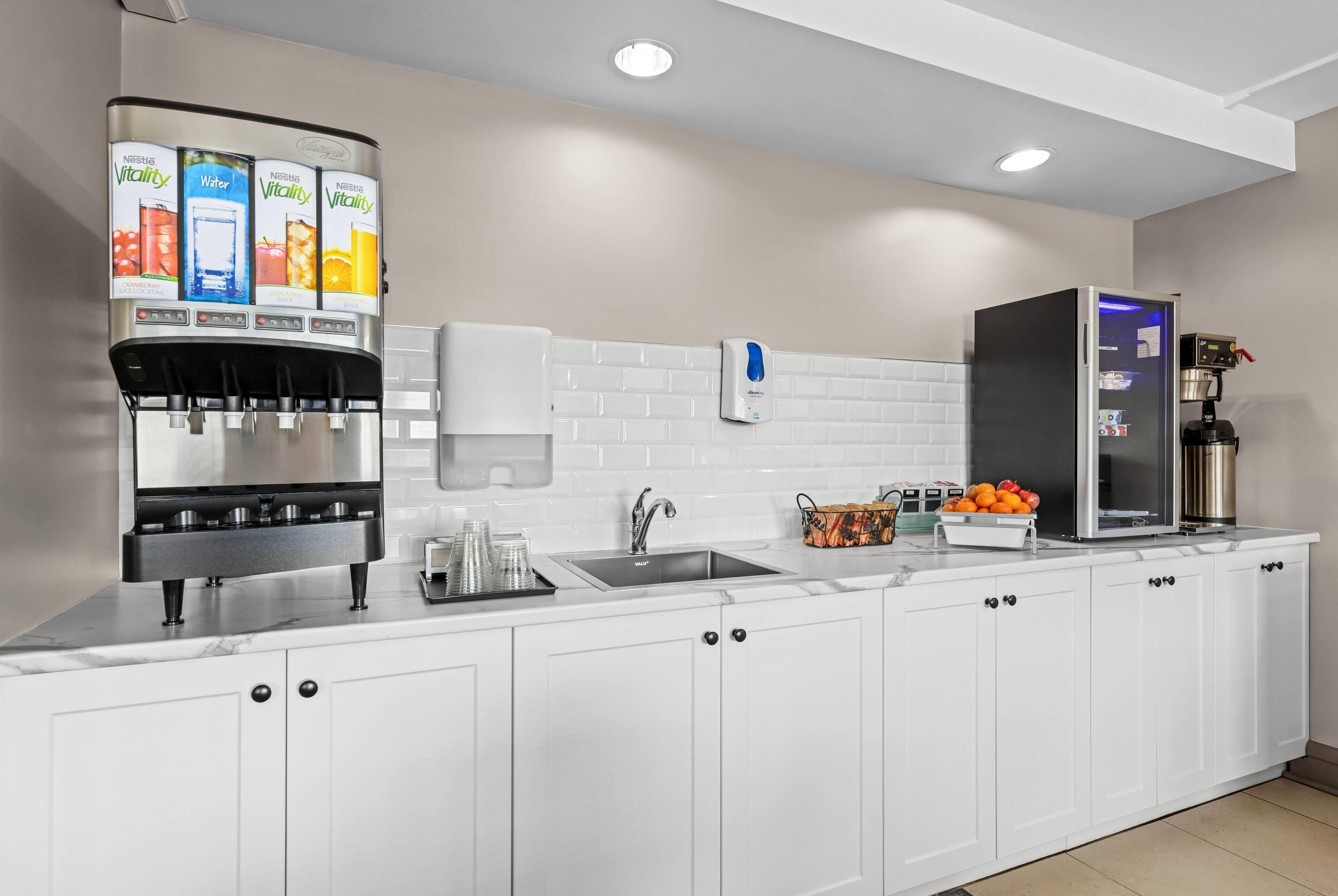 A modern kitchen with a water dispenser, a coffee machine, and a refrigerator.