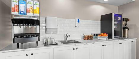 A modern kitchen with a water dispenser, a coffee machine, and a refrigerator.