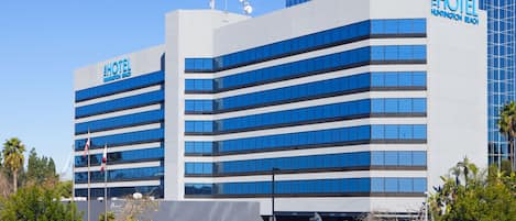 A modern hotel building with multiple floors, large windows, and a prominent sign.
