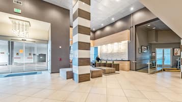 A spacious lobby with a reception desk, seating areas, and a clear exit sign.