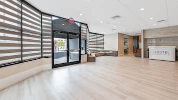 Un moderno vestíbulo de hotel con una zona de estar curva, una recepción y amplias ventanas que ofrecen vistas de la calle.