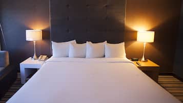 Habitación de hotel con una cama grande, dos mesitas de noche con lámparas, un teléfono y una silla.