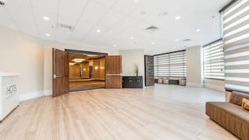 A spacious hotel lobby with a wooden floor, a reception desk, and a seating area with a sofa and cushions.
