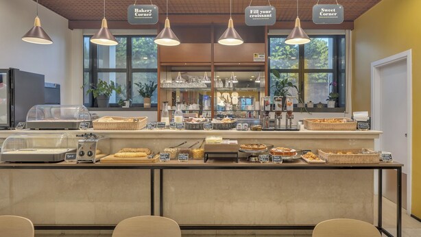 Un comptoir de boulangerie où sont exposés divers produits de boulangerie, ainsi qu’un espace dédié aux boissons chaudes.