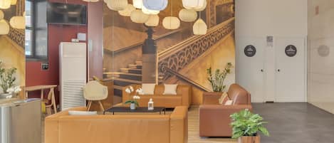 En moderne lobby med et stort mural af en trappe, behagelige siddepladser og hængende papirlanterner.