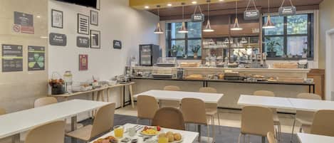 A breakfast area with tables and chairs, a counter with food items, and a television mounted on the wall.